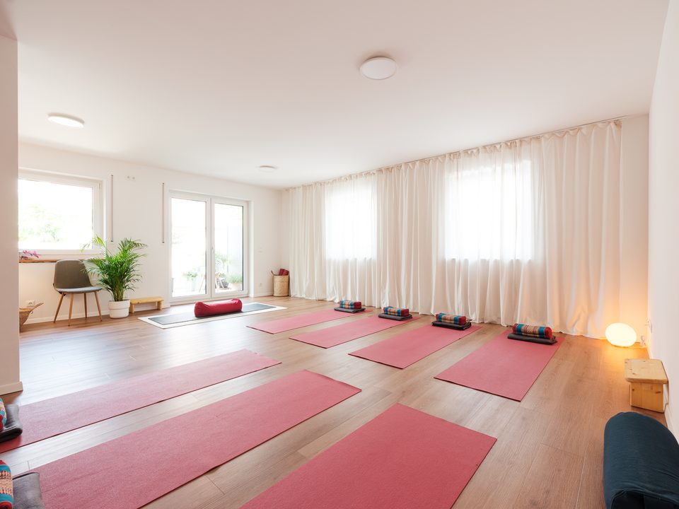 Weiterer Blick in den Yogaraum mit Matten und großem Fensterlicht