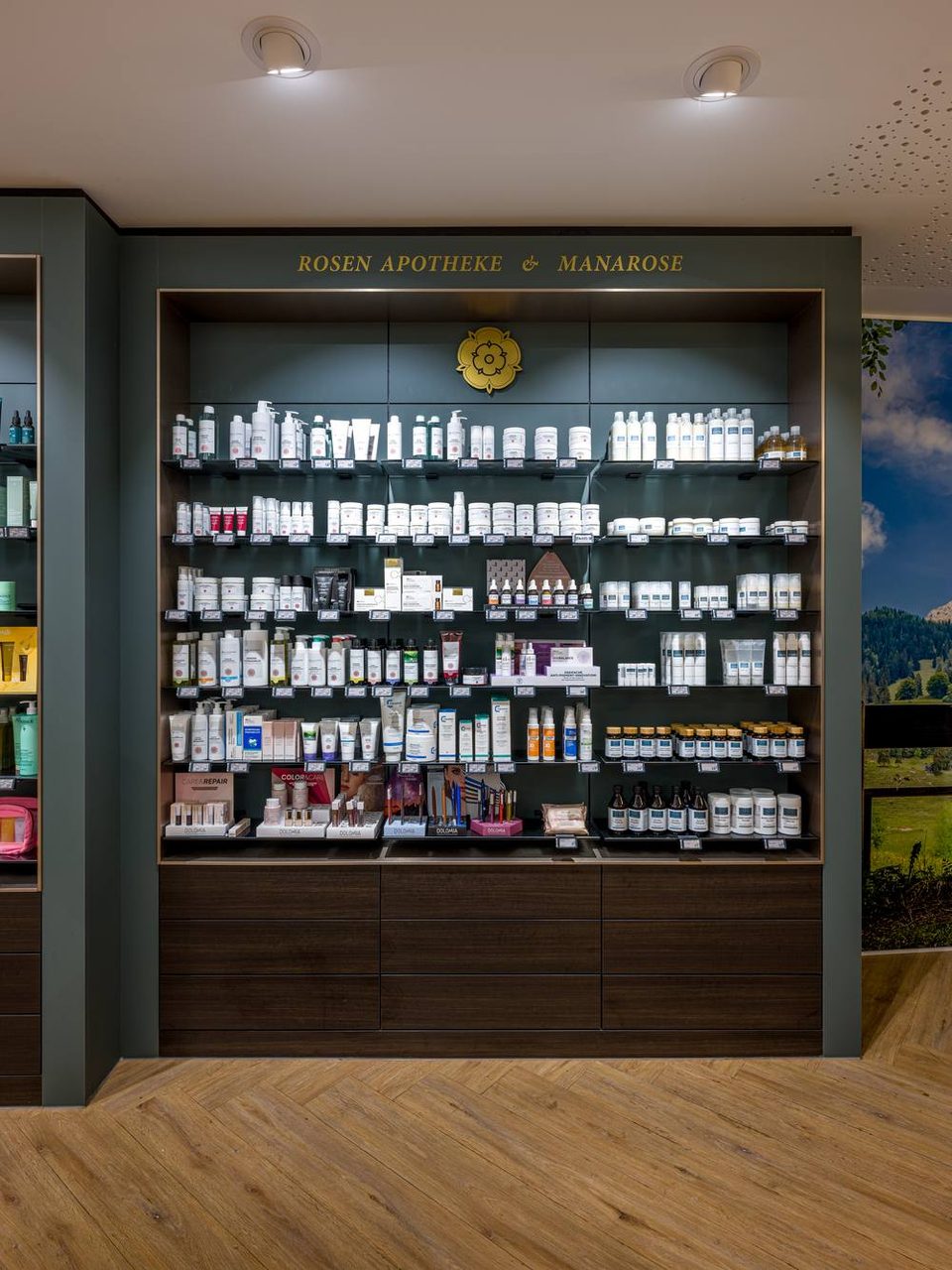 Freiwahlregal der Rosen-Apotheke mit dunkelgrüner Wand und goldener Rose