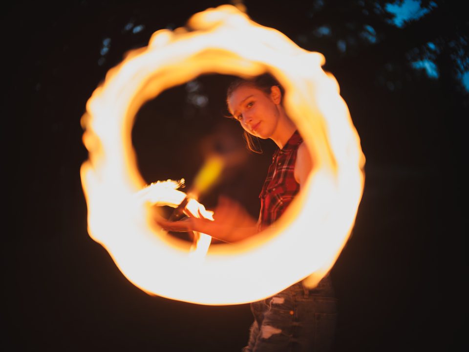 Portrait einer jungen Frau beim Feuerjuggling im Feuerschein auf der Burgruine Brennberg