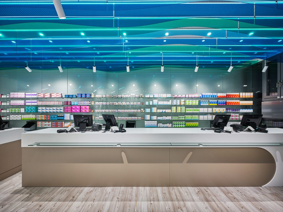 Offizin der See-Apotheke: die Theke vor der Sichtwahl, darüber die blaugrüne Wellendecke aus transluzenten Paneelen