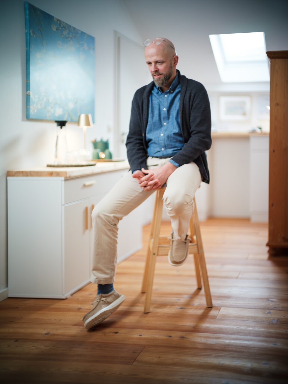 Porträt von Timo Jansen auf einem hohen Hocker in seiner Praxis