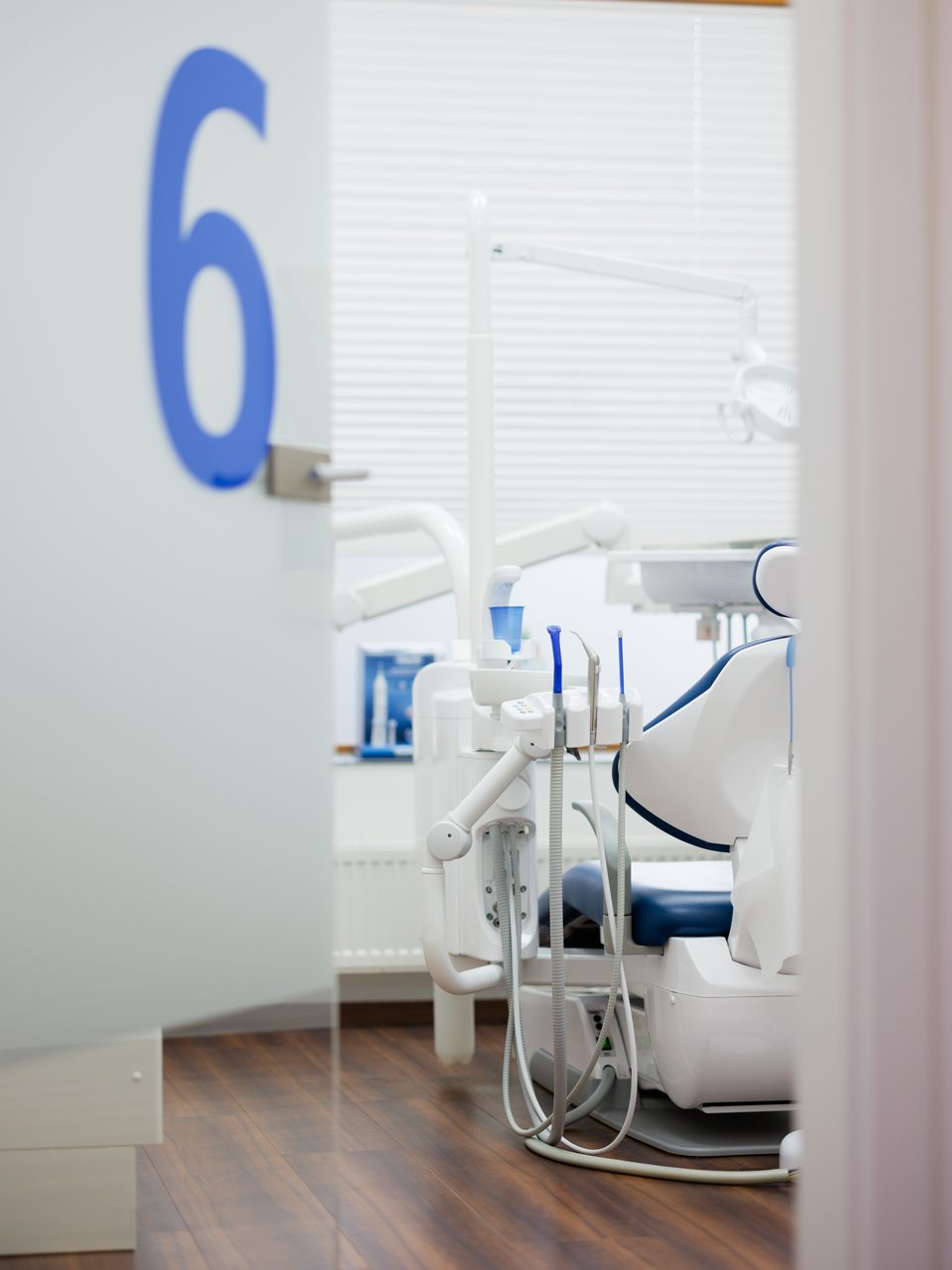 Behandlungszimmer 6, die blaue Ziffer steht groß auf der Glaswand vor dem Stuhl